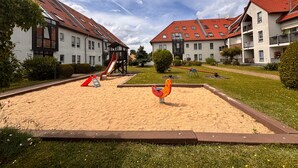 Ein Wohngebiet mit einem Spielplatz, einschließlich Rutsche und Schaukeln, umgeben von Häusern mit roten Ziegeldächern.