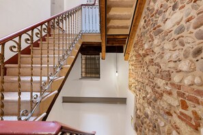 Eine Treppe mit schmiedeeisernem Geländer, einer Steinmauer und einem Fenster mit Gitterstäben.