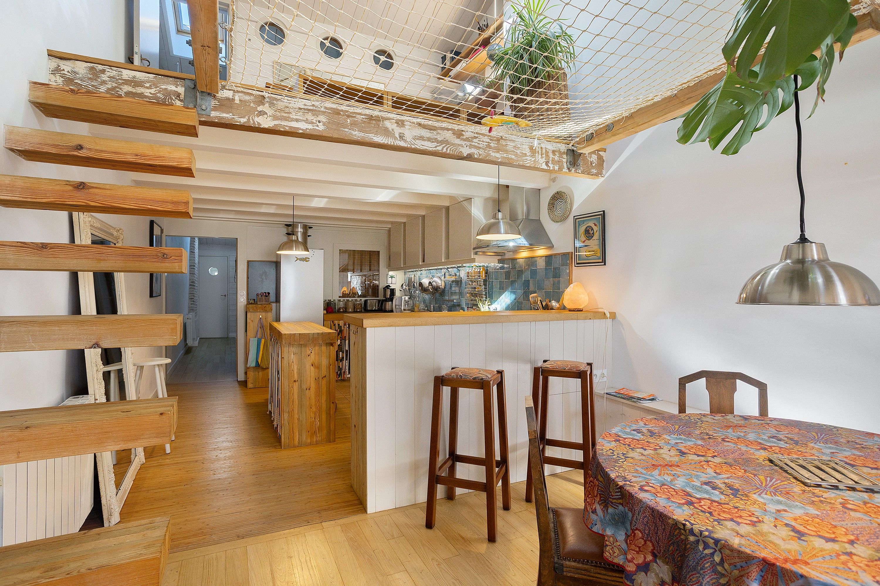Una cocina moderna con vigas de madera, una hamaca colgante y una zona de comedor con mantel colorido.