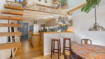 Una cocina moderna con vigas de madera, una hamaca colgante y una zona de comedor con mantel colorido.