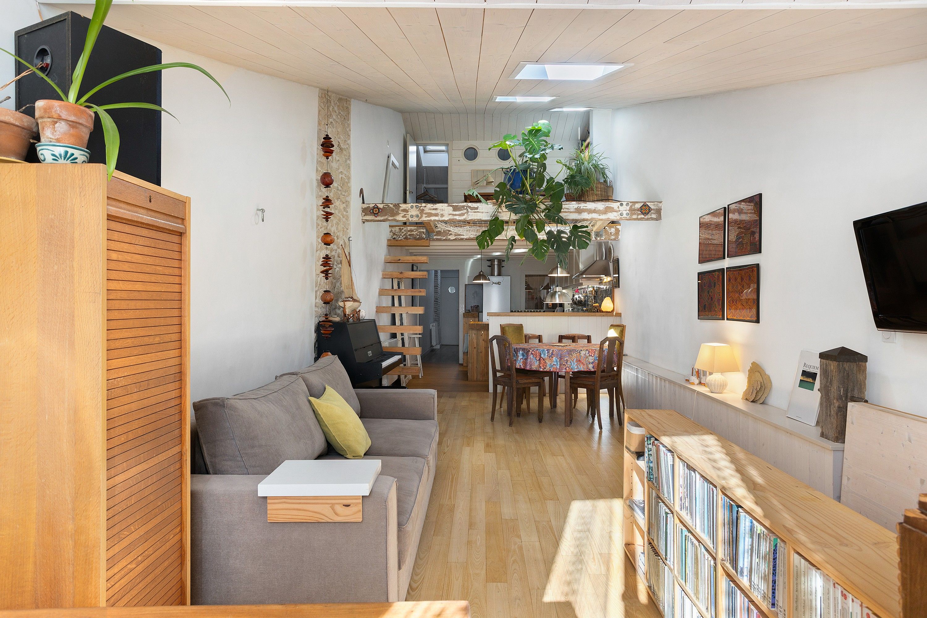 Uma sala de estar aconchegante com um sofá cinza, um armário de madeira e um espaço de refeições com mesa e cadeiras.