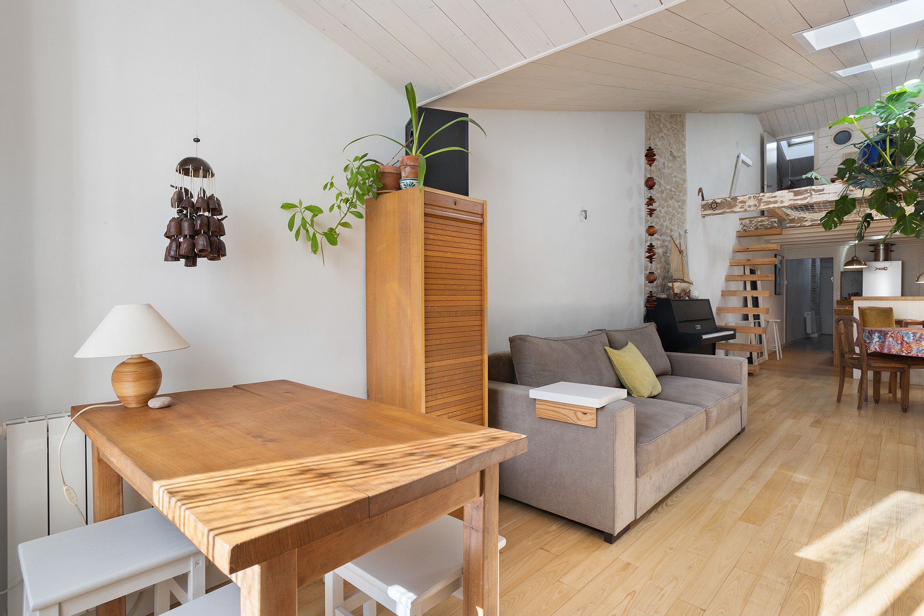 Una sala de estar con una mesa de madera, un sofá, una lámpara y una planta.