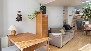 Una sala de estar con una mesa de madera, un sofá, una lámpara y una planta.