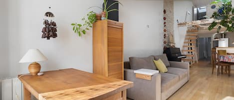 Una sala de estar con una mesa de madera, un sofá, una lámpara y una planta.