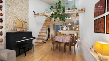 A cozy living space with a piano, a dining table, and a staircase leading to an upper level.