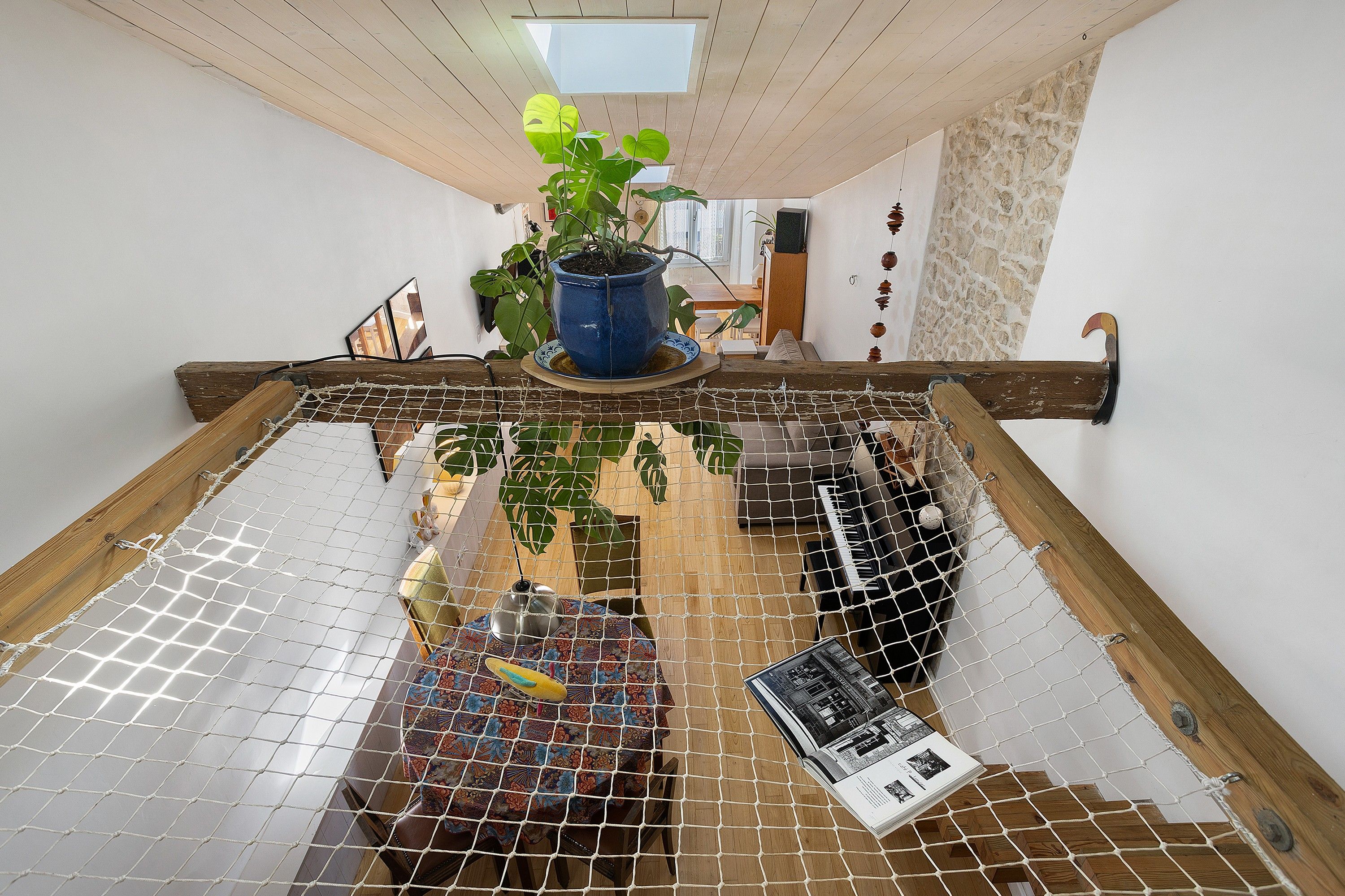 A room with a net-covered floor, a potted plant, and a piano.