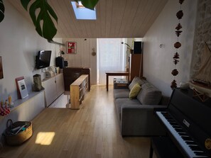 Un salon comprenant un piano, un canapé, un téléviseur et un meuble en bois.