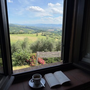 A window with a view of a green landscape, a cup of coffee, and an open book on a windowsill. - Palazzo Goduto - Organic Farm Retreat in Umbria, Italy (Perugia)