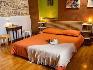 Een netjes ingerichte slaapkamer met een bed, nachtkastjes, een lamp en een groene muur.