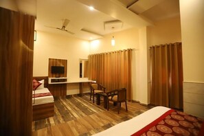 A hotel room with a bed, a desk, a chair, a television, and a ceiling fan.