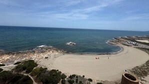 A beach with a sandy area, a rocky shoreline, and a clear sky.