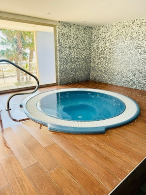 An indoor swimming pool with a tiled mosaic wall and wooden flooring.