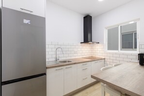 Uma cozinha moderna com geladeira de aço inoxidável, forno embutido, pia e janela com vidro jateado.