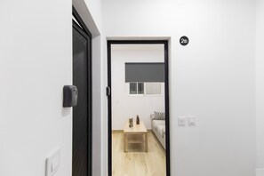 A hallway leading to a room with a bed, a small table, and a window. - Vacation Apartment 'Camacho 2B' with Wi-Fi (Las Palmas de Gran Canaria)