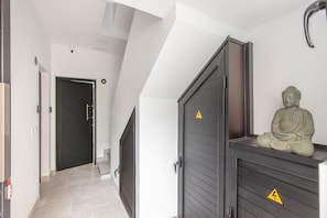 Ein Flur mit einer dunklen Tür, einer Statue und einem Warnschild an einem Schrank.