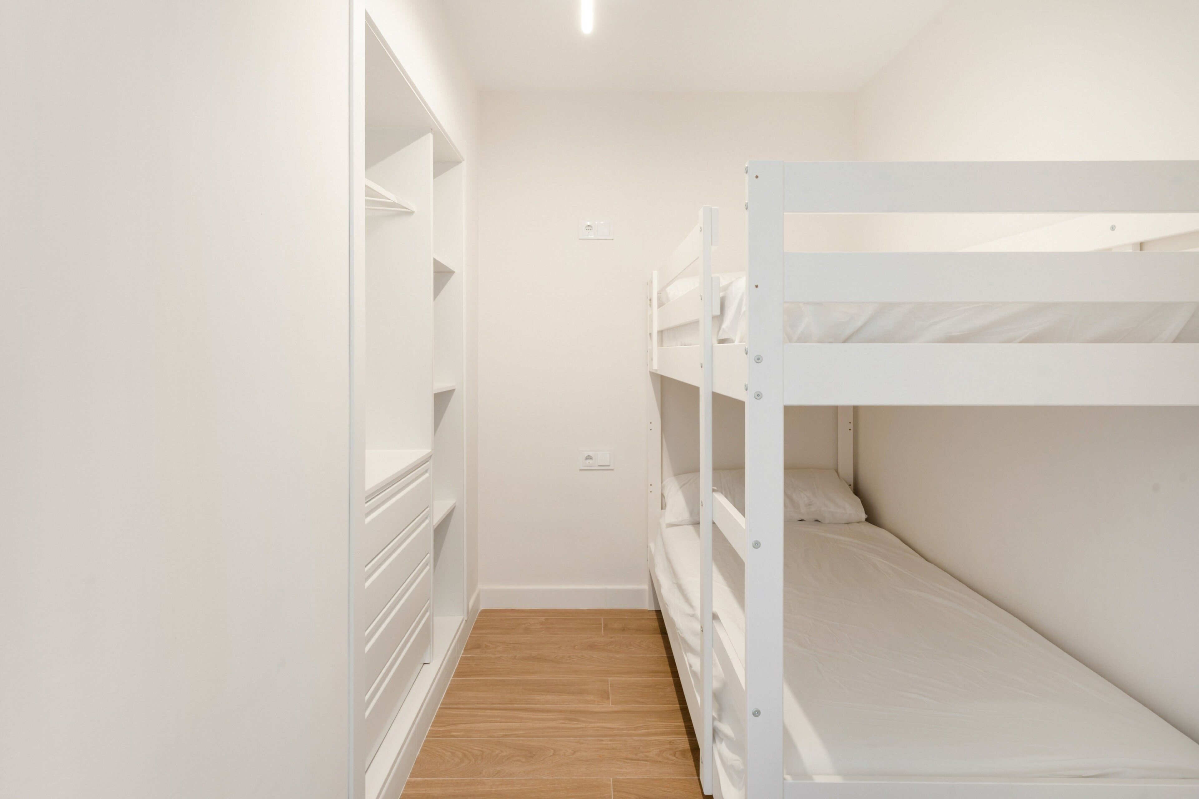 A bunk bed room with a wooden floor and white walls.