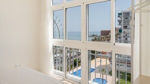 Ein Zimmer mit großem Fenster, das einen Pool und Meerblick bietet.
