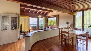 A wooden interior with a dining area, a built-in cabinet, and a view of the outdoors. - Groovy House: Vintage Charm, Lake Views, and Nature Retreat (Agra)