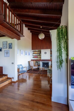 A spacious living area with wooden flooring, a fireplace, and a staircase.