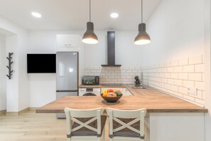 Una cocina moderna con una isla de madera, dos lámparas colgantes, un horno empotrado y un televisor de pantalla plana.