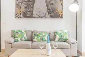 Ein Wohnzimmer mit einer Couch, zwei Kissen, einer Champagnerflasche und zwei Gläsern auf einem Tisch.