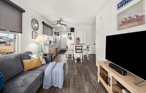 Ein Wohnzimmer mit einer Couch, einem Fernseher und einem Essbereich mit Stühlen und einem Tisch.