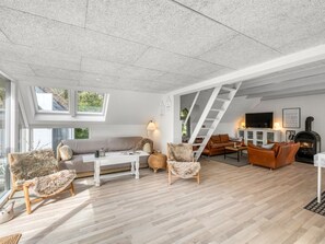 Ein großzügiger Wohnbereich mit hoher Decke, einer Treppe, einem Kamin und einem großen Fenster.