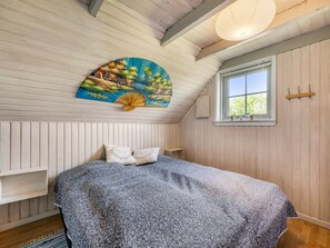 Ein Schlafzimmer mit einem Bett, einem Fenster, einem Wandventilator und einem dekorativen Gemälde.