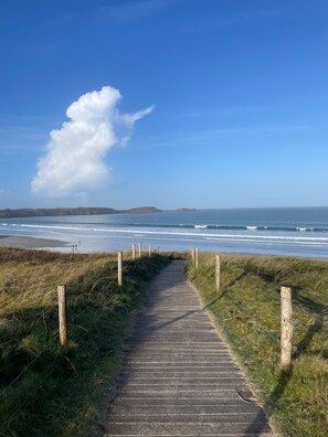 Un sentier en bois qui mène à une plage offrant une vue sur l’océan.