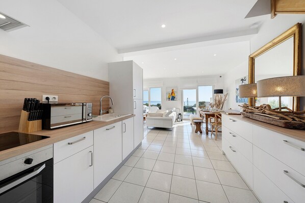 A modern kitchen with a built-in oven, a sink, and a dining area with a table and chairs.