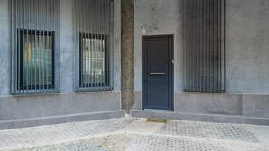 En modern byggnad med en mörk dörr, gallerförsedda fönster och en vägg med en tydlig struktur.