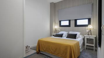 A bedroom with a bed, two bedside lamps, a window, and a curtain.