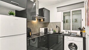 A compact kitchen with a built-in washer and dryer, a microwave, and a coffee maker. - Holiday Home 'Lobo's House' with Sea View, Private Terrace and Wi-Fi (Câmara de Lobos)