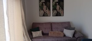 A living room with a sofa, pillows, and two framed artworks on the wall. - Holiday Home 'Lobo's House' with Sea View, Private Terrace and Wi-Fi (Câmara de Lobos)