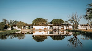 A serene lakeside property with a white building, a wooden dock, and lush greenery. - Mas de Dard, an Exceptional Estate in Provence, with a heated pool and a padel court (Saintes-Maries-de-la-Mer)