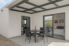 A modern outdoor patio with a dining table and chairs, a glass door leading to a bedroom, and a ceiling with a grid pattern. - Casa El Limonero: Private Pool, Wi-Fi & Air Conditioning in Conil de la Frontera (Conil de la Frontera)