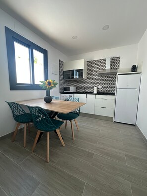 Eine moderne Küche mit Essbereich, ausgestattet mit einem Holztisch, grünen Stühlen und einer Vase mit einer Sonnenblume.