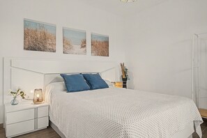 A bedroom with a bed, two bedside tables, a nightstand, and wall-mounted artwork. - Casa El Limonero: Private Pool, Wi-Fi & Air Conditioning in Conil de la Frontera (Conil de la Frontera)