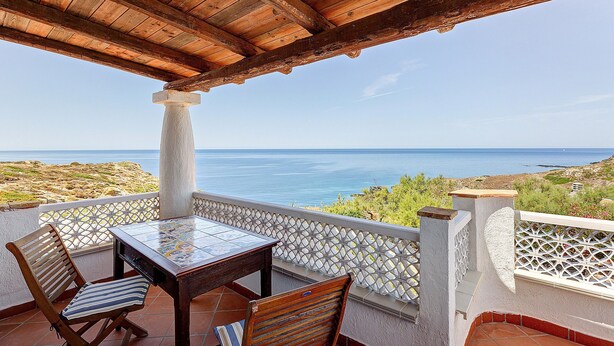 A wooden pergola with a tiled table and chairs overlooking a coastal view. - Panoramic Apartment in Villa (Torre dei Corsari)
