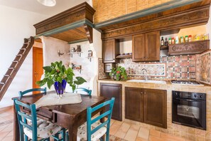 A kitchen with wooden cabinets, a stove, and a sink. - Panoramic Apartment in Villa (Torre dei Corsari)