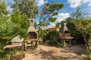 Outdoor stone ovens, a concrete structure, and surrounding greenery. - Panoramic Apartment in Villa (Torre dei Corsari)