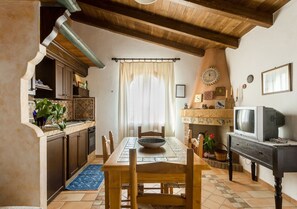 A dining area with a wooden table, chairs, a bowl, and a television on a stand. - Panoramic Apartment in Villa (Torre dei Corsari)