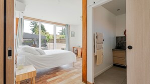 A modern bedroom with a bed, bedside table, and a view through a large window.