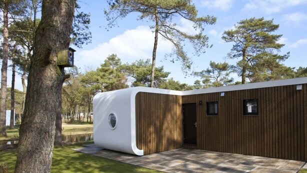 A modern, single-story building with a wooden exterior, a circular window, and a door.