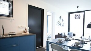 A modern kitchen with a blue countertop, a sink, and a dining area with a table and chairs.