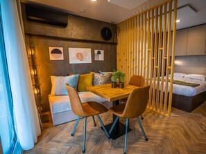 Een moderne kamer met een houten eettafel, twee stoelen, een bank en een bed.