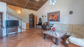 Un amplio espacio de sala con televisor, sofá, mesa de centro y una escalera que sube a un nivel superior.