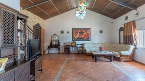 Un salón espacioso con techo de madera, un cuadro grande, un sofá, una mesa de centro y una televisión.