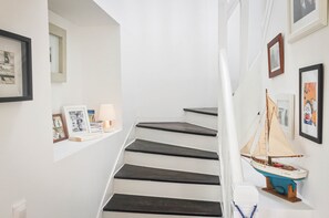 Eine Treppe mit dunklen Stufen, ein kleines Bootsmodell und Bilder in Rahmen an den Wänden.