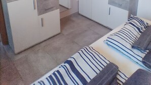 Moderni, hyvin valaistu huone, jossa on sohva, pieni purjevenemalli ja ruukkukasveja.